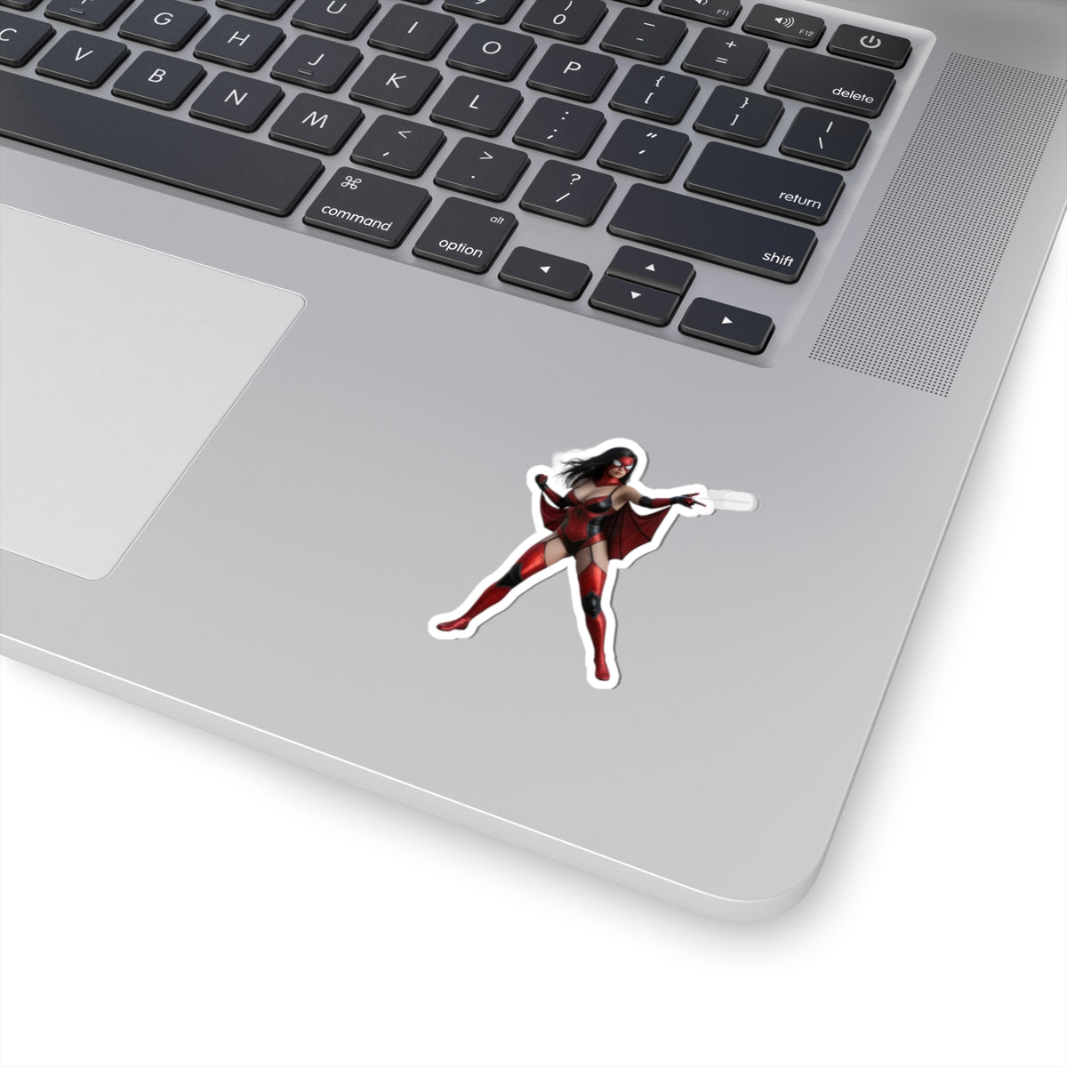 Spider Woman Sticker – Comic Heroine Vinyl Sticker for Laptops & Indoor Decor on silver laptop, glossy red-and-black comic heroine vinyl sticker applied